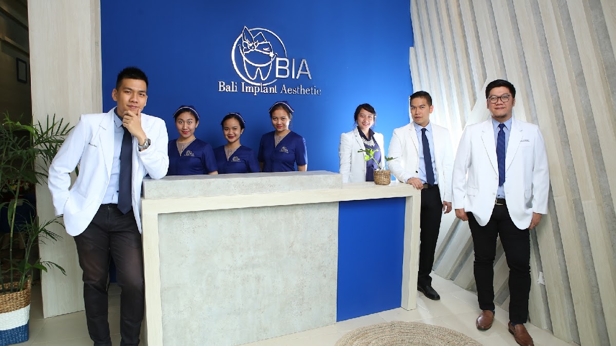 The full BIA dental team of seven poses professionally at the branded reception desk, with doctors in white coats and staff in coordinated navy uniforms.