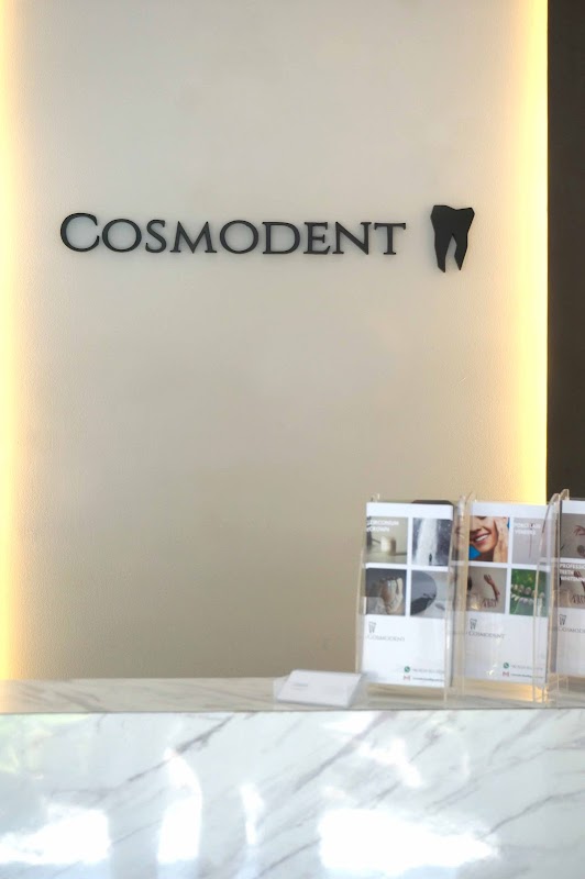 Cosmodent Bali reception desk with prominent backlit branding and marble countertop