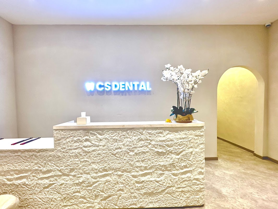 CS Dental Canggu elegant reception with stone front desk, illuminated CS Dental signage, and orchid