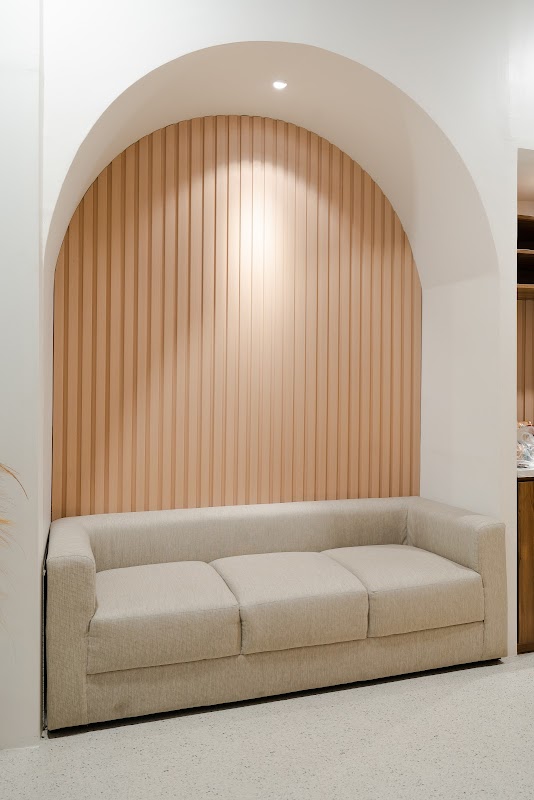 Cozy waiting area nook with arched wooden alcove and cream sofa at Fidelity Dental Bali