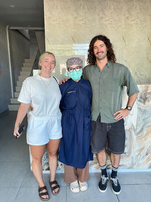 Flash Dental Bali staff member posing warmly with two happy patients outside the clinic