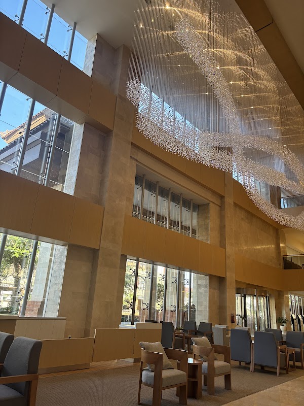 Stunning double-height lobby with an elaborate crystal chandelier installation, large windows providing natural light, and stylish seating areas.