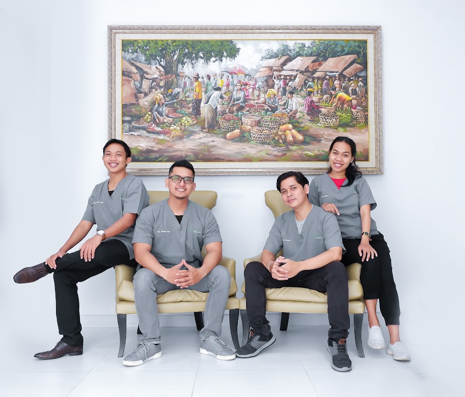 Rejuvie Dental Center team of four dental professionals in grey scrubs smiling casually under Balinese artwork