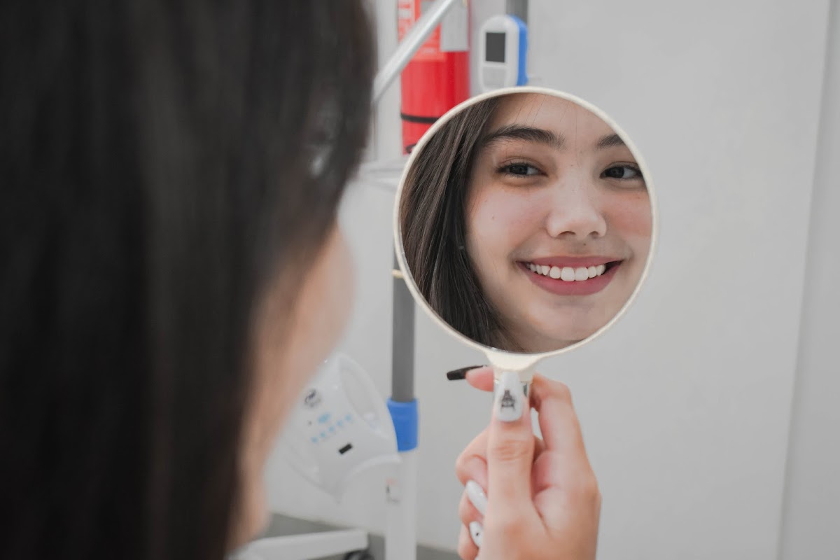 Happy patient admiring her smile in mirror after treatment at Smile Ready Bali