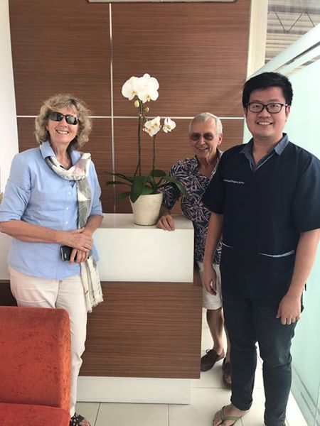 Modern reception area of Sunset Dental Bali with illuminated logo wall and marble front desk